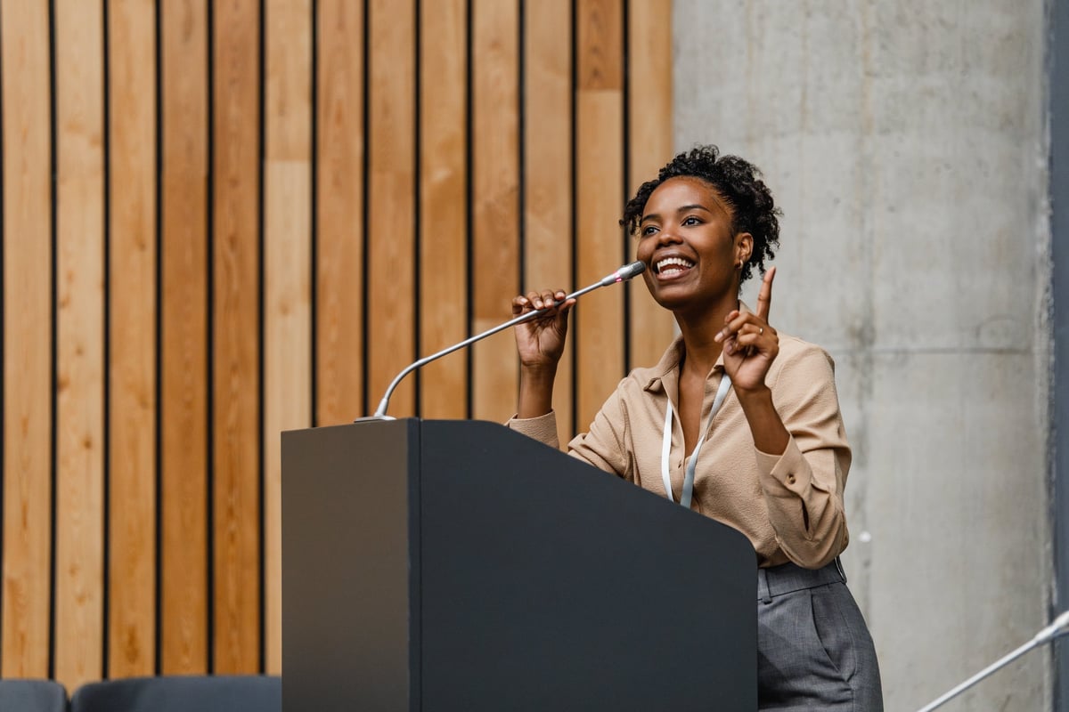 Young professional woman delivering a confident, engaging presentation at a conference podium