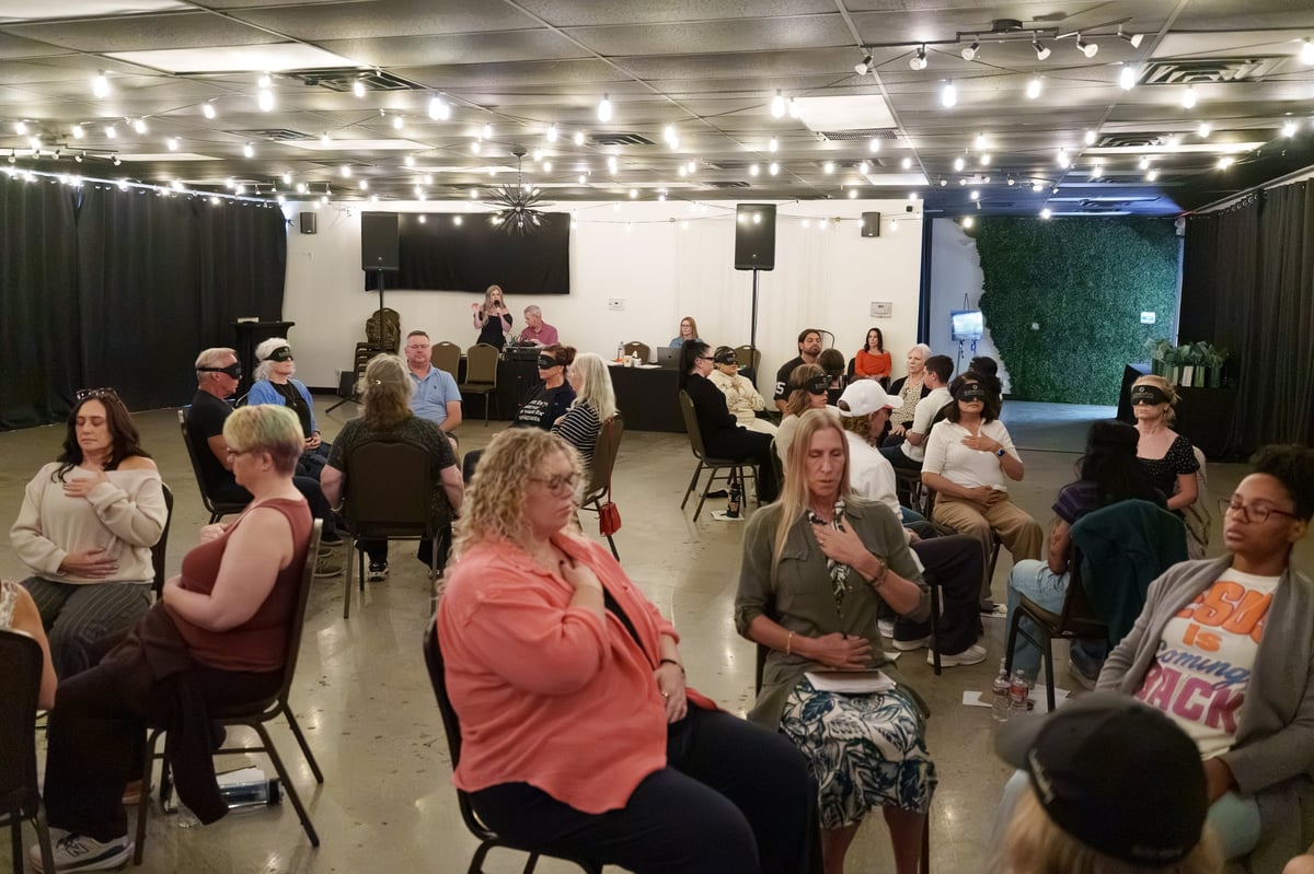Group of diverse people seated in chairs during an indoor workshop or community event in a well-lit venue