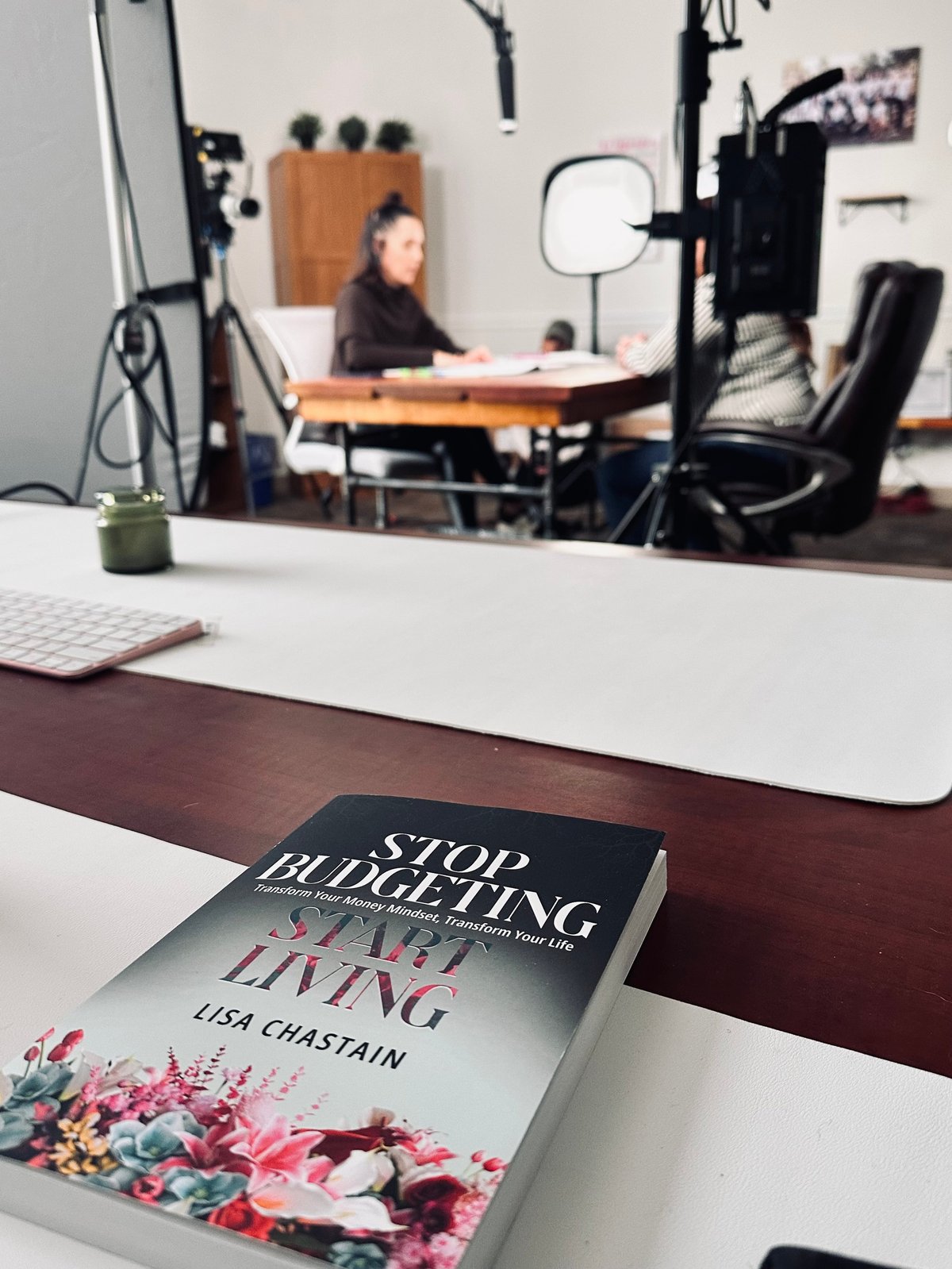 Book Stop Budgeting Start Living by Lisa Chastain on desk with studio setup in background