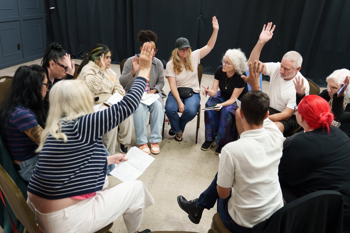 Group of diverse people sitting in a circle during a community meeting or support group session.