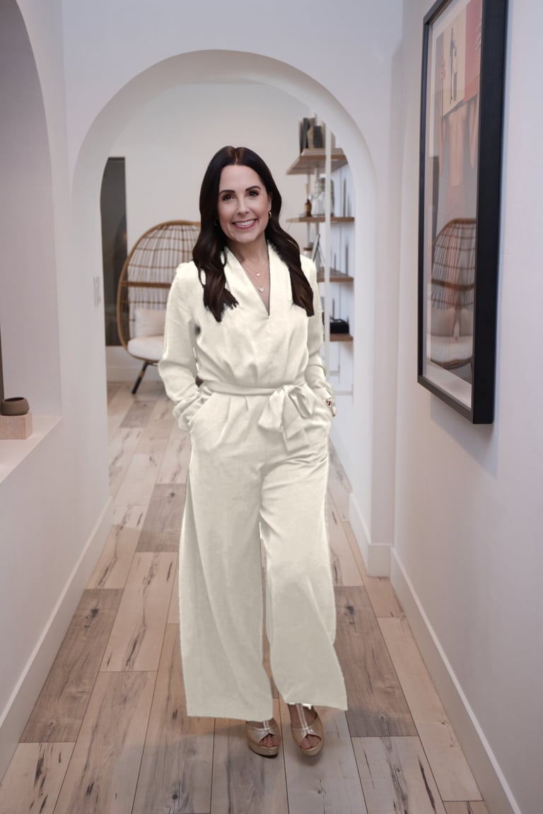 Woman in white wrap dress standing in a modern hallway with an arched entryway and wooden flooring
